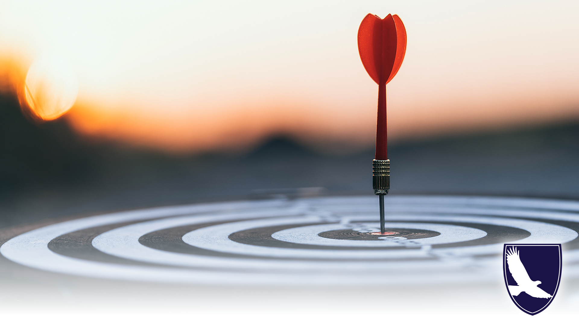 Close up red dart arrow hitting target center dartboard on sunset background